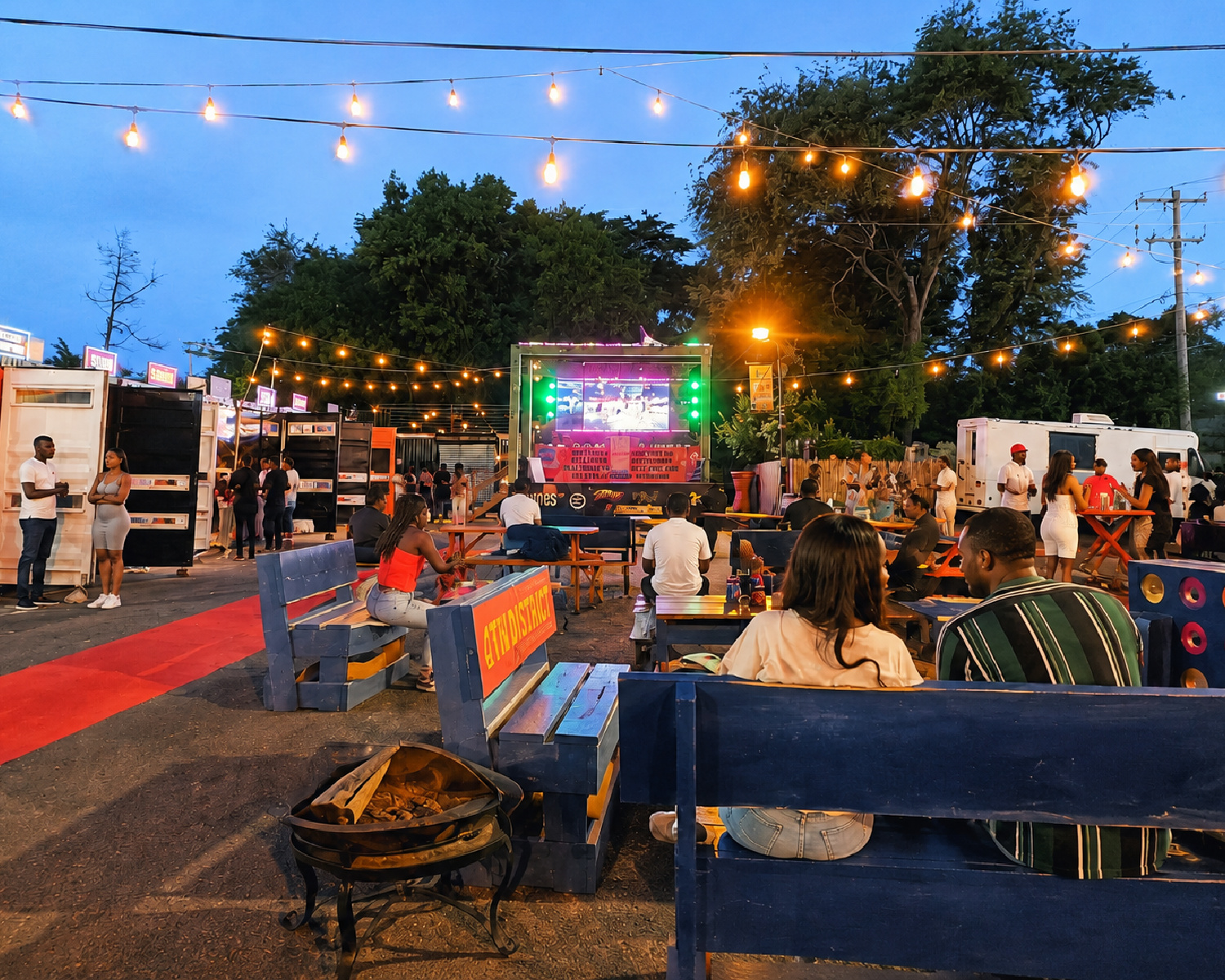 People gather under string lights at the 4th District Container Village in West Philly.