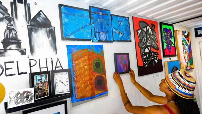 Exhibit A hangs artwork inside her Container Village studio for 250 Years Black in America.
