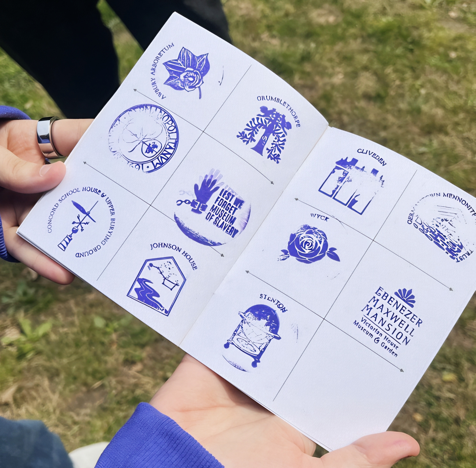 Hands holding a stamped Historic Germantown passport booklet during the Green Spaces Stamp Rally.