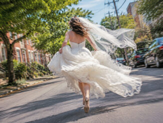 Runaway bride in a flowing wedding dress racing down a Philadelphia street