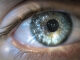 Close-up of a human eye reflecting scattered points of light, illustrating Lyn Godley’s research on immersive art and the body.