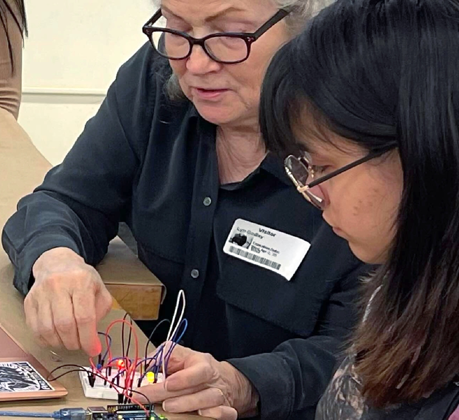 Lyn Godley helps a participant work with a small electronic circuit during a volunteer event at Community College of Philadelphia.