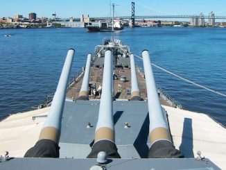 Battleship New Jersey’s 16-inch guns point toward the Delaware River and Ben Franklin Bridge.